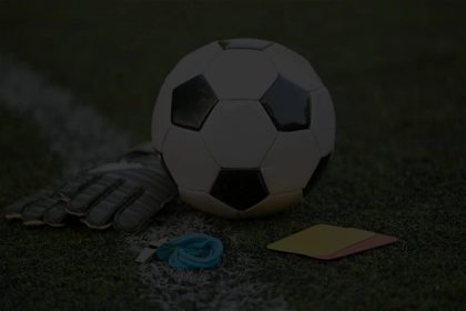 Balón de fútbol, guantes de portero y tarjetas en una cancha