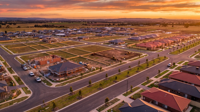 Aerial view of a planned DHA-style housing society at golden hour showing rapid development and rising plot values — MyProperties Lahore