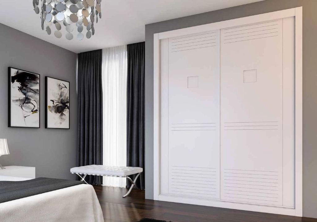 Puertas correderas de armario empotrado en fresado especial y lacado blanco, en un dormitorio, composición slim.