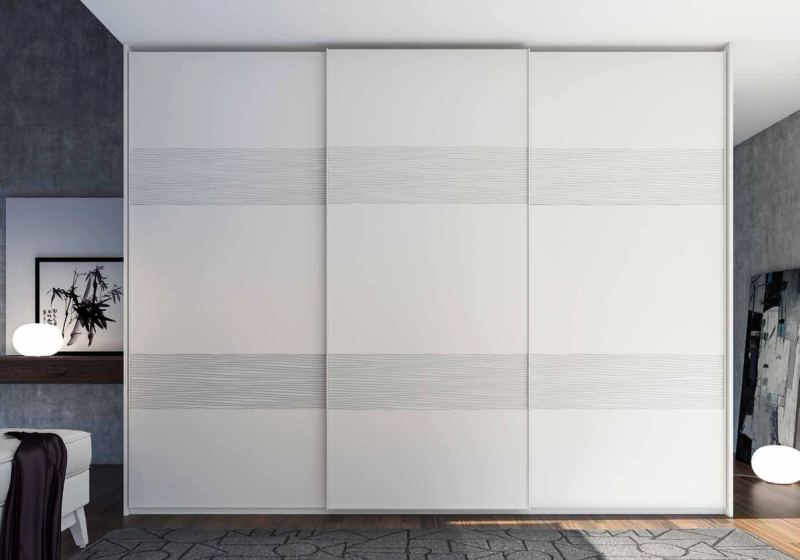 Puertas correderas de armario empotrado en tablero de una única pieza fresado especial y lacado blanco, en un dormitorio, composición tempro.