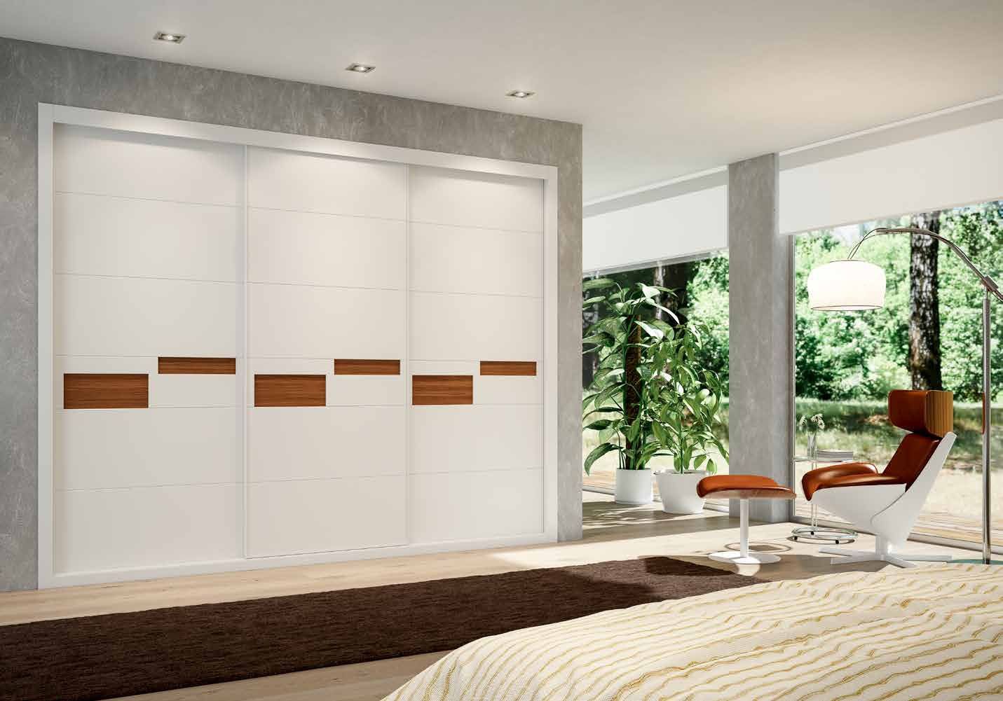Puertas correderas de armario empotrado en tablero de una única pieza fresado especial y lacado blanco tablero trasero nogal canaletto, en un dormitorio, composición slim.