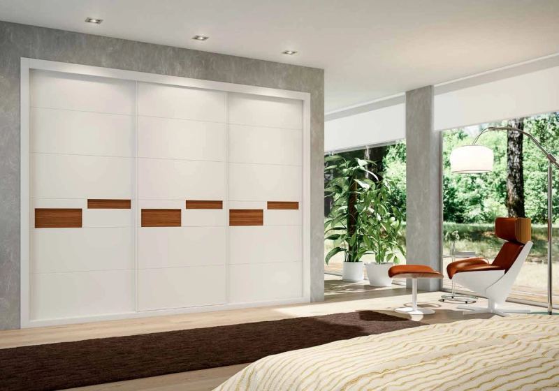 Puertas correderas de armario empotrado en tablero de una única pieza fresado especial y lacado blanco tablero trasero nogal canaletto, en un dormitorio, composición slim.