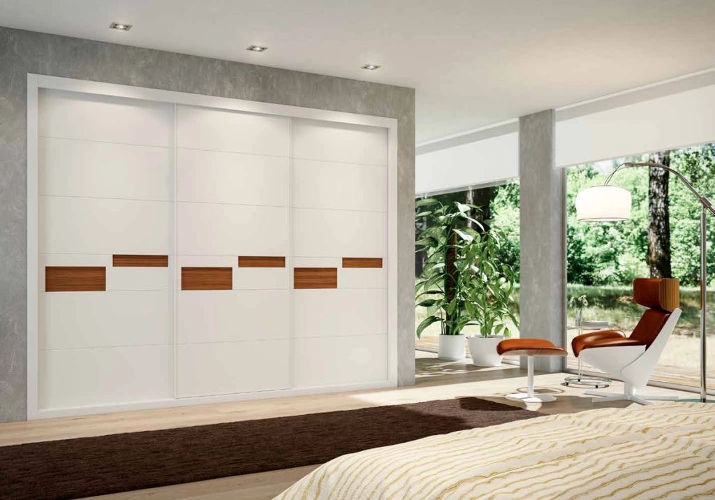 Puertas correderas de armario empotrado en tablero de una única pieza fresado especial y lacado blanco tablero trasero nogal canaletto, en un dormitorio, composición slim.