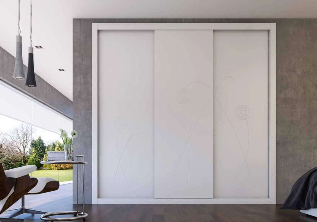 Puertas correderas de armario empotrado en fresado flor y lacado blanco, en un dormitorio, composición lite.