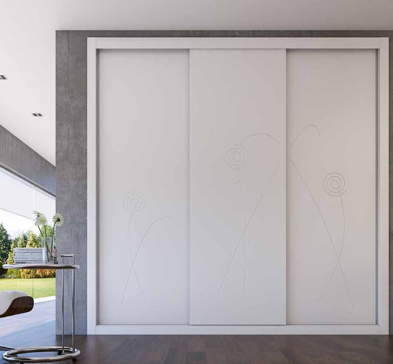 Puertas correderas de armario empotrado en fresado flor y lacado blanco, en un dormitorio, composición lite.