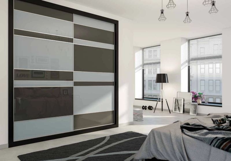 Puertas correderas de armario empotrado en gris claro, vidrio gris antracita, en un dormitorio, composición slim.