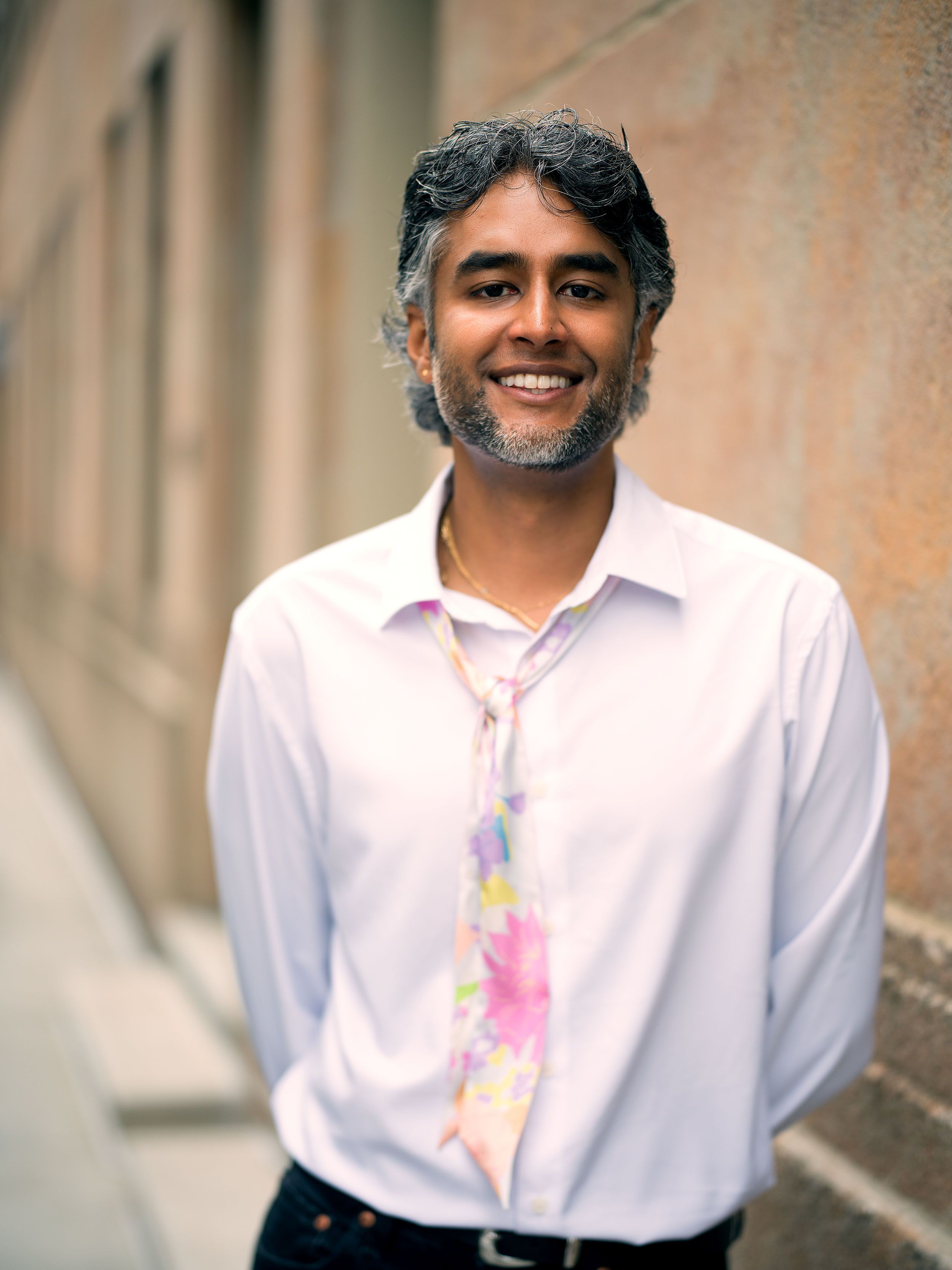 A headshot of a South Asian person with nice salt-and-pepper hair and a well-kept beard.