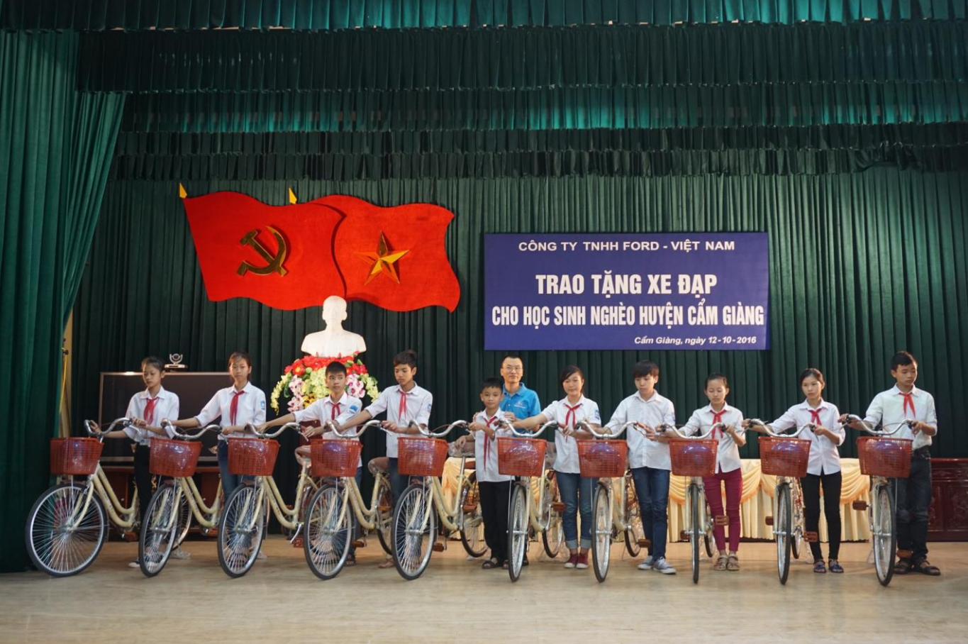 Trinh Van Ngan, Plant Manager of Ford Vietnam (center), presents the bicycles and helmets to students in Cam Giang District.