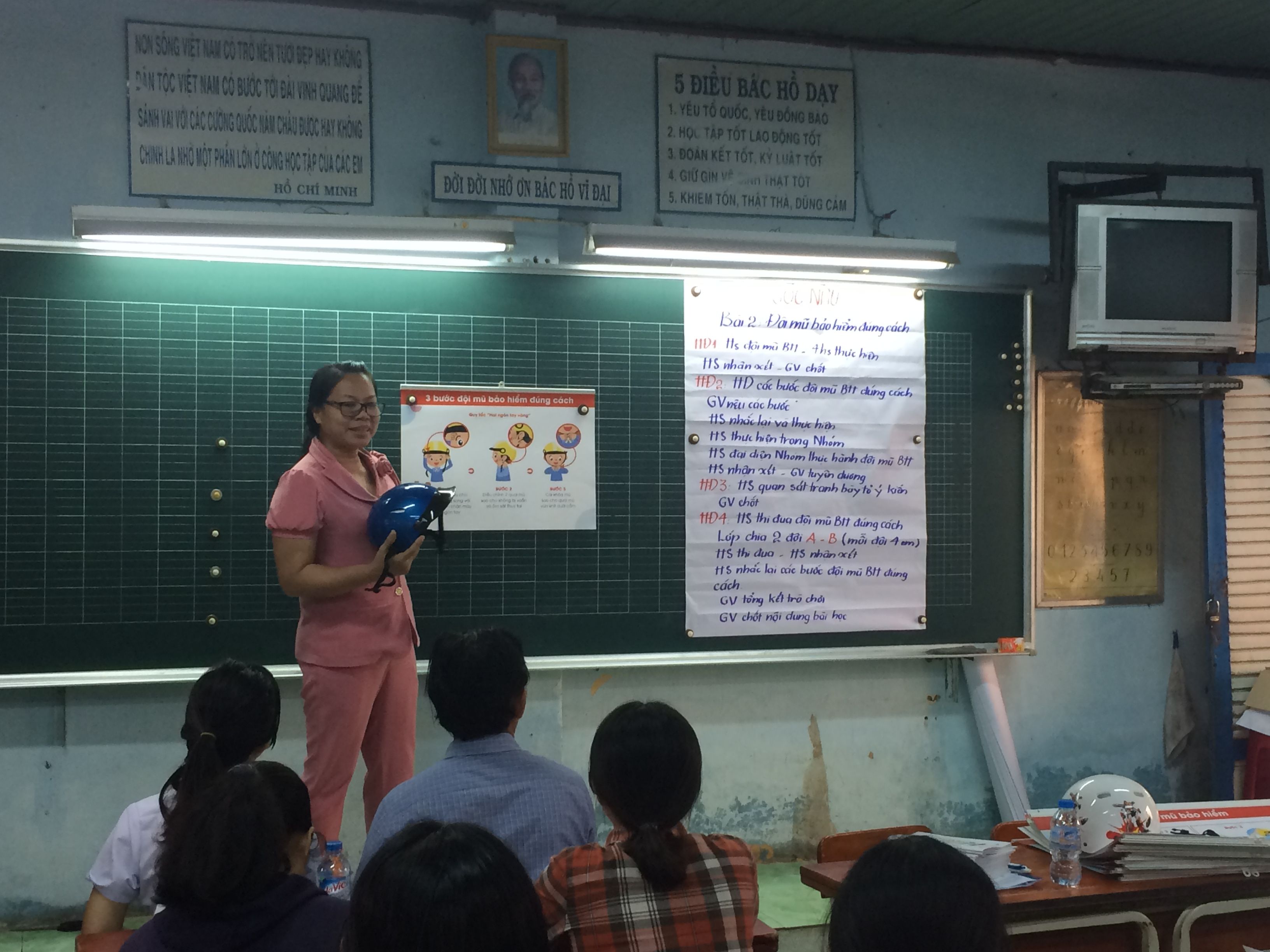 A teacher demonstrates the steps for properly wearing a helmet.