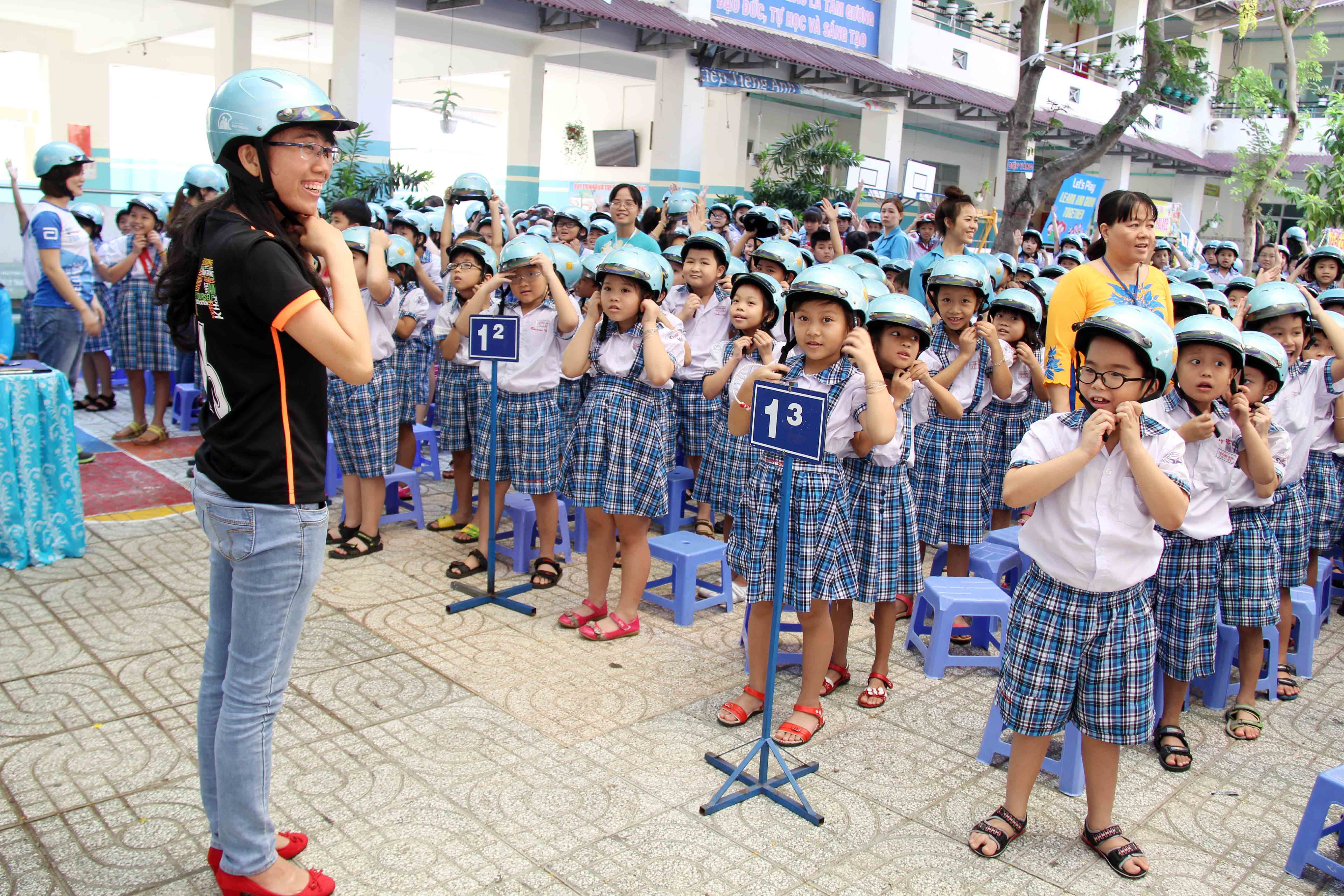 Abbott volunteers teach students how to wear their new helmets correctly.