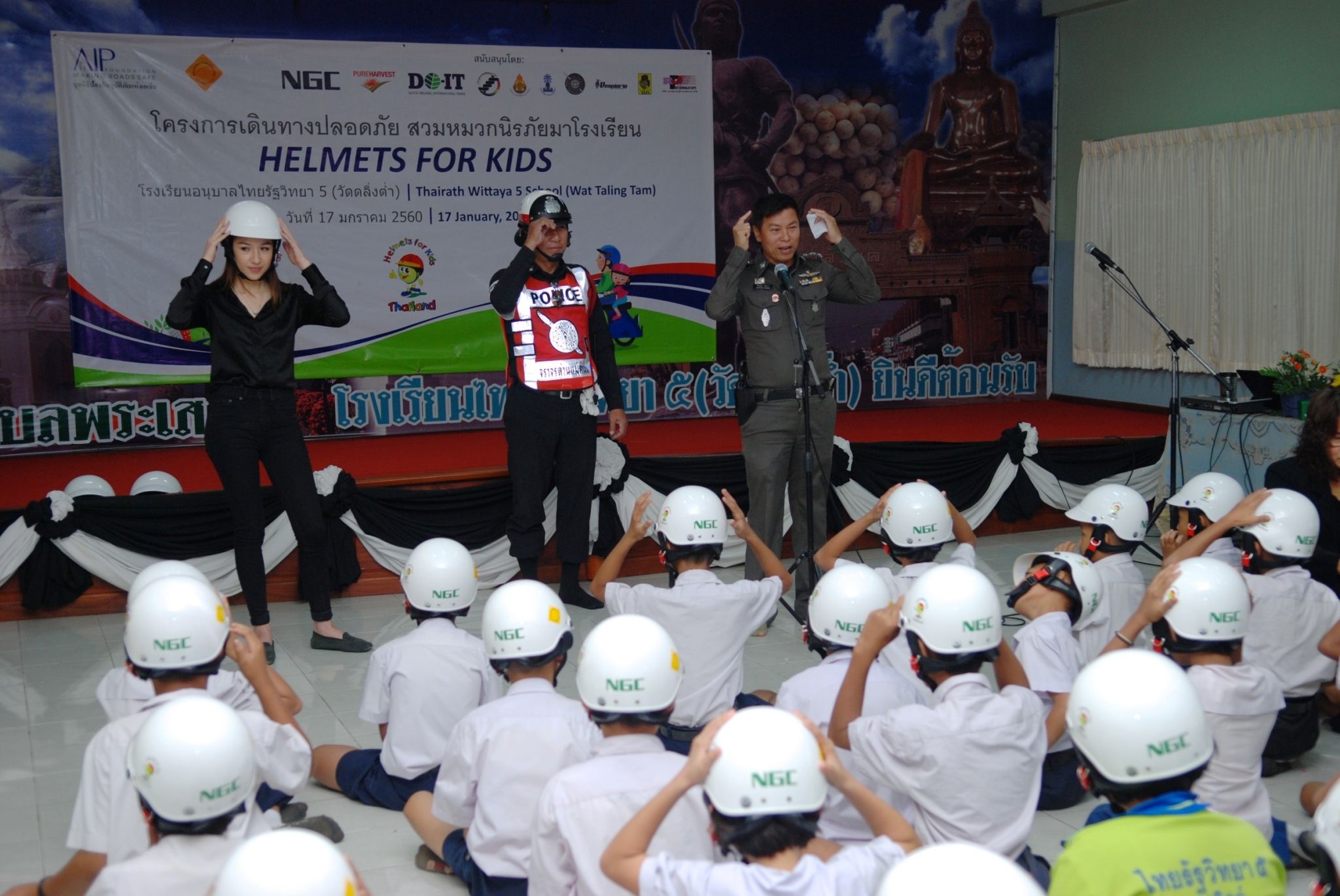 Police officers teach students how to properly wear their new helmets.