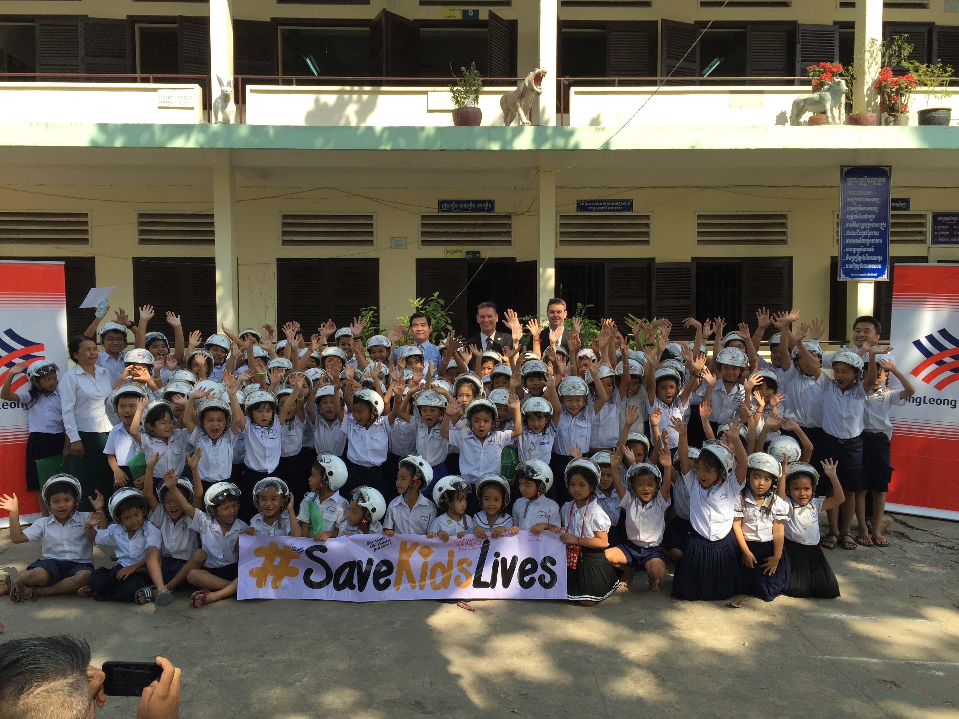 Students at Anuk Wat Primary School are joined by representatives from Hong Leong Bank Cambodia Plc. during the helmet handover ceremony in Phnom Penh.