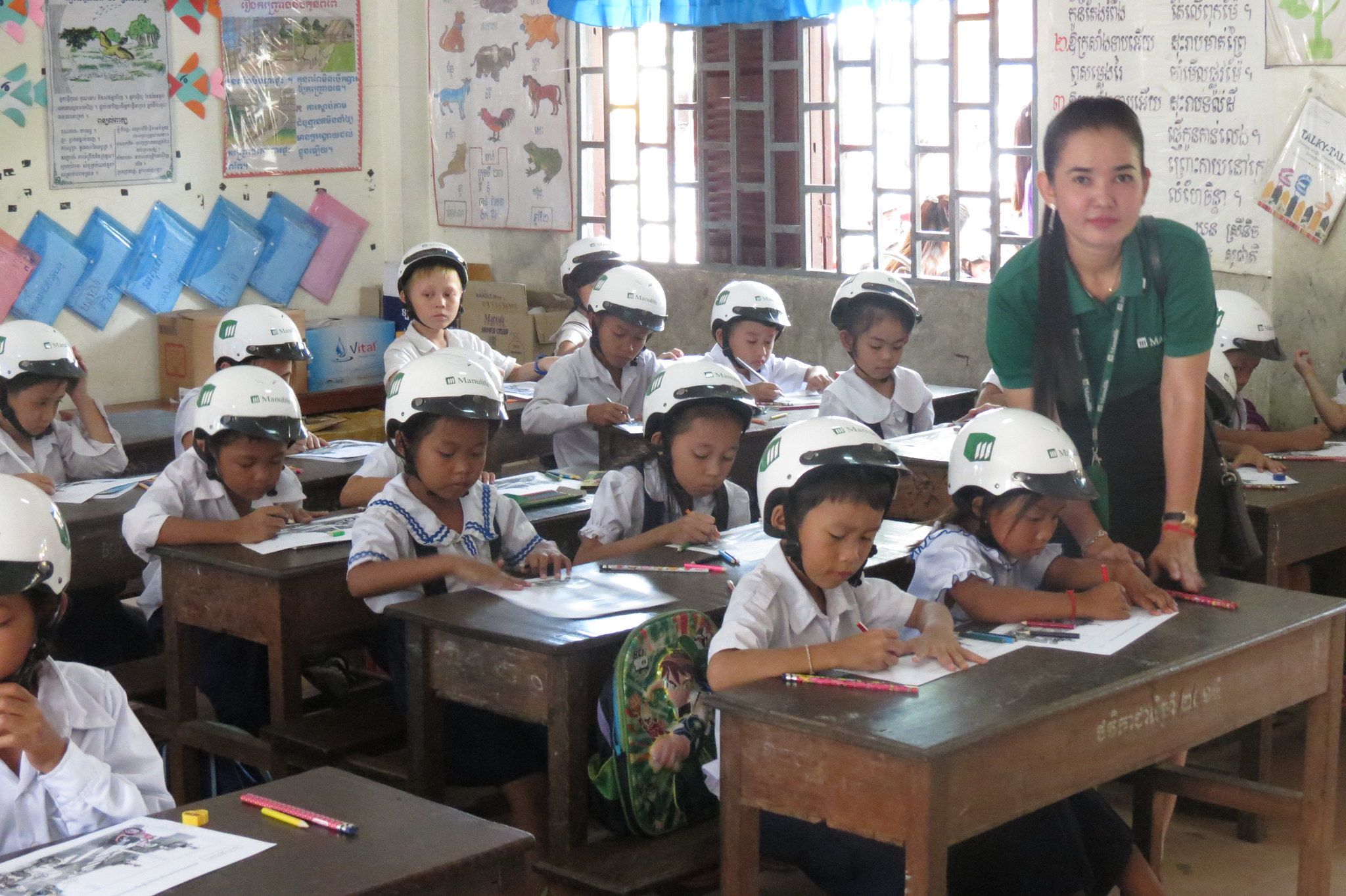 A Manulife Cambodia volunteer works with students from Veal Vong Primary School as part of a road safety awareness activity.