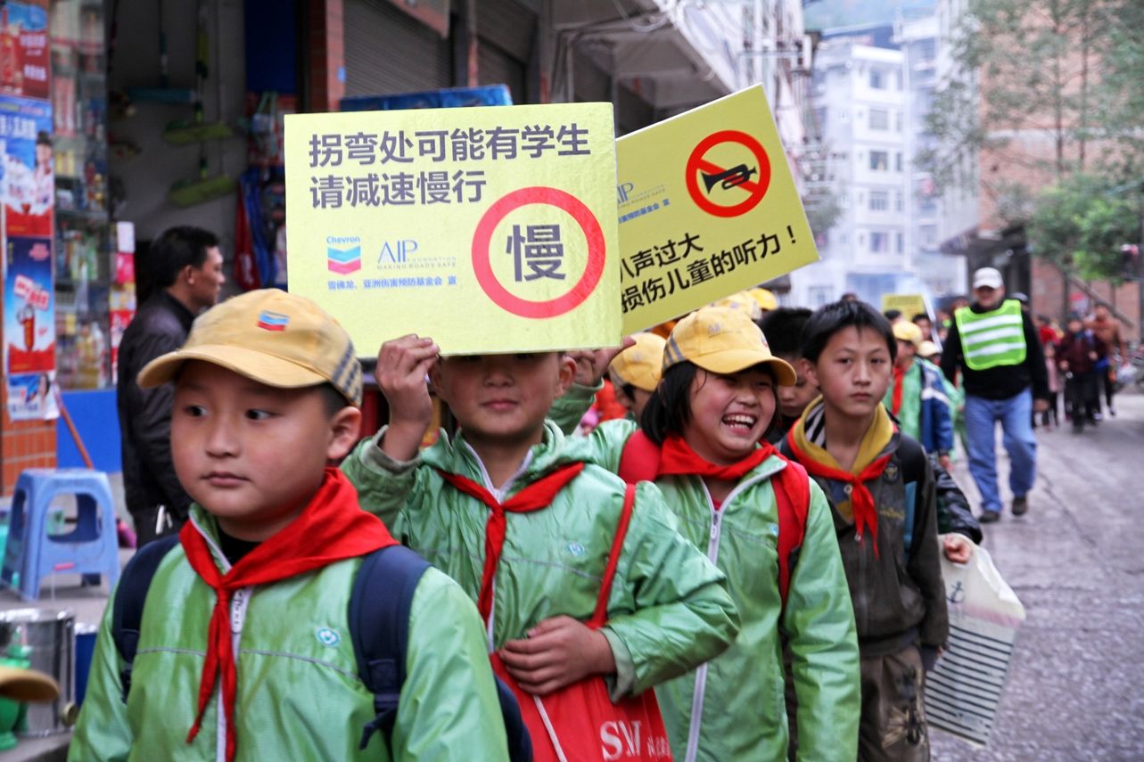 Students from Qili Primary School in Kai County, China, along with AIP Foundation and Chevron staff, participate in a Walking School Bus to increase pedestrian safety awareness on National Road Safety Day