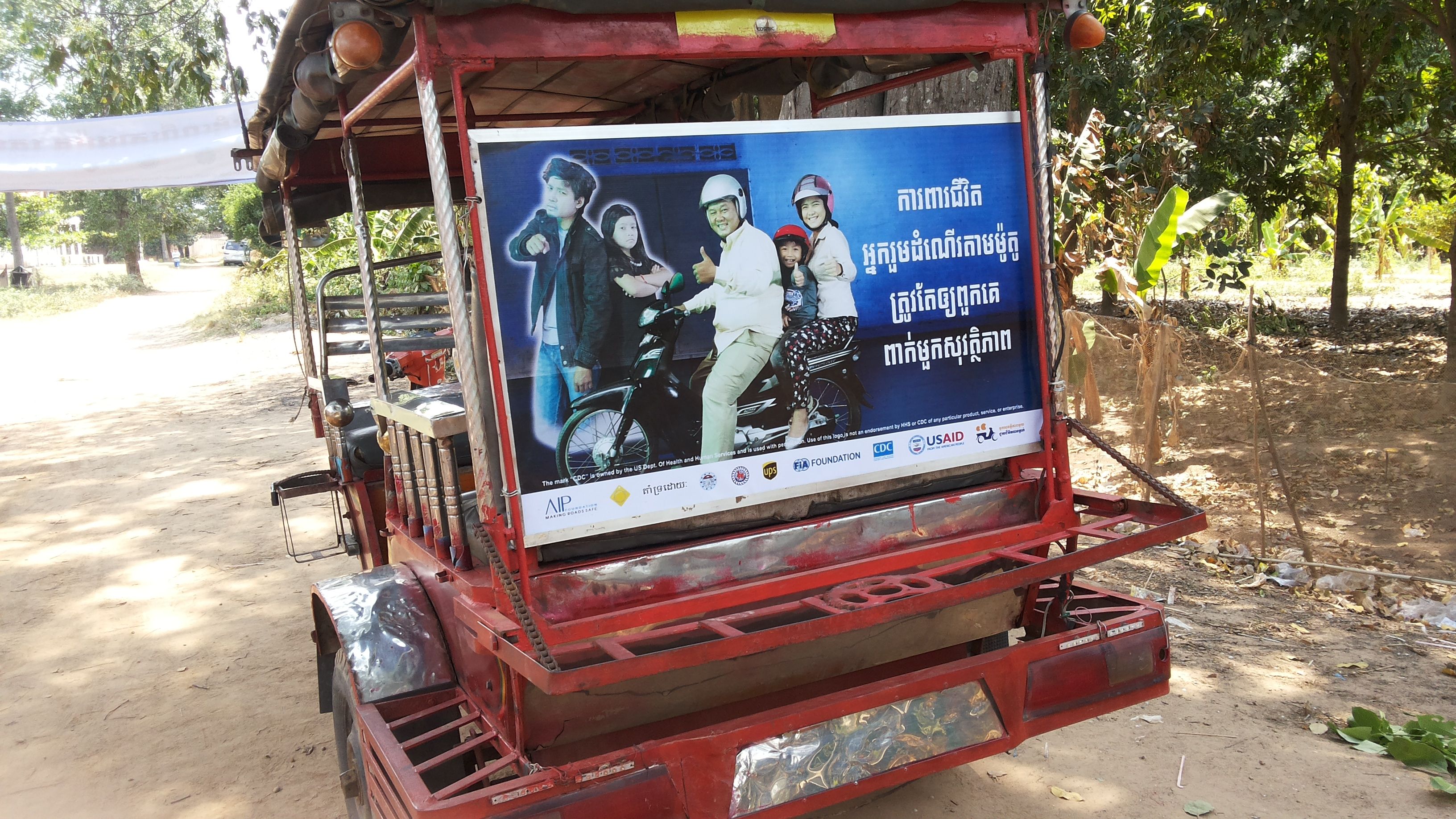A tuk tuk panel with the message, “Protect your passengers’ lives. Make sure they wear helmets.” is driven throughout the commune