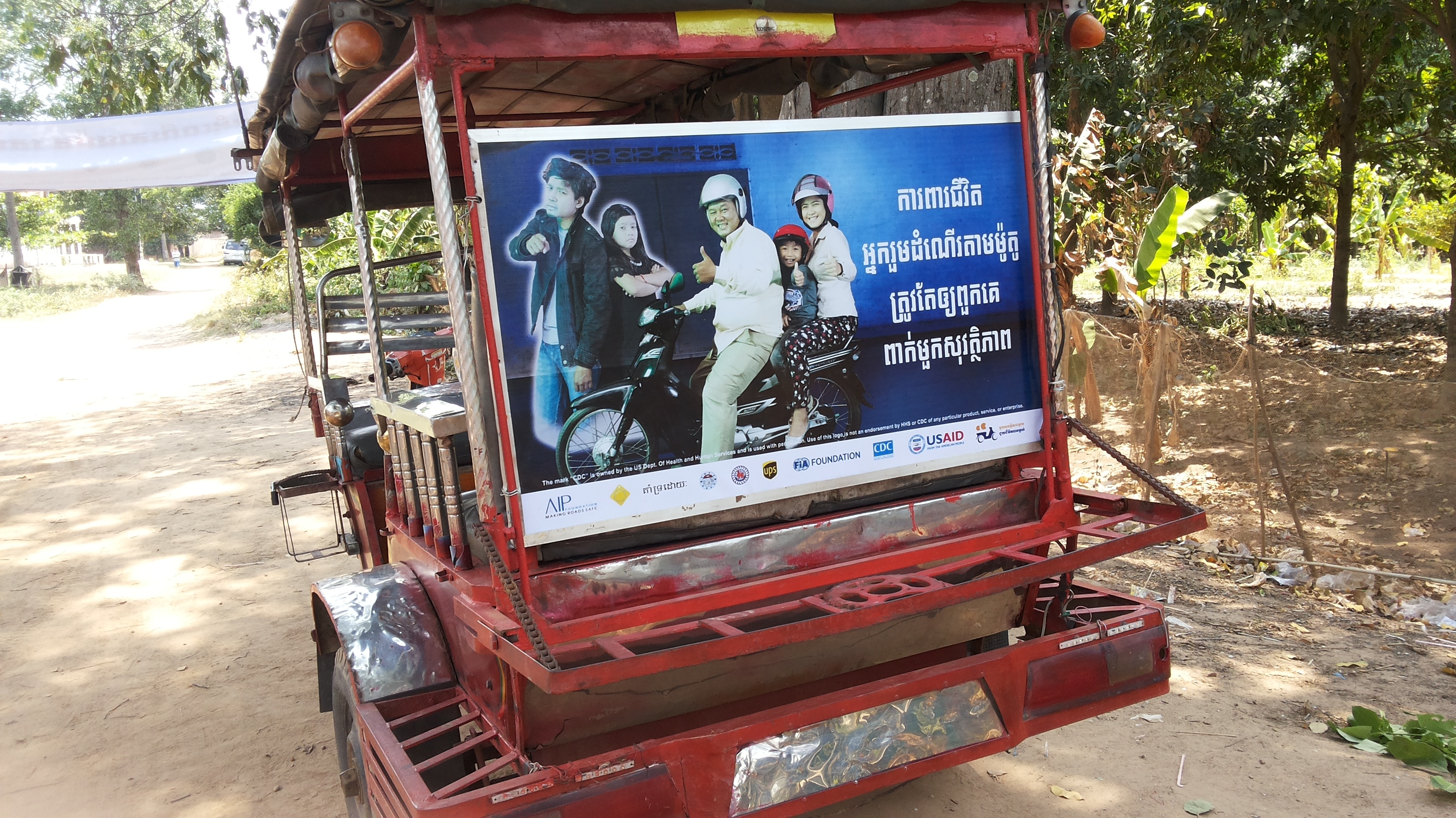 A tuk tuk panel with the message, “Protect your passengers’ lives. Make sure they wear helmets.” is driven throughout the commune