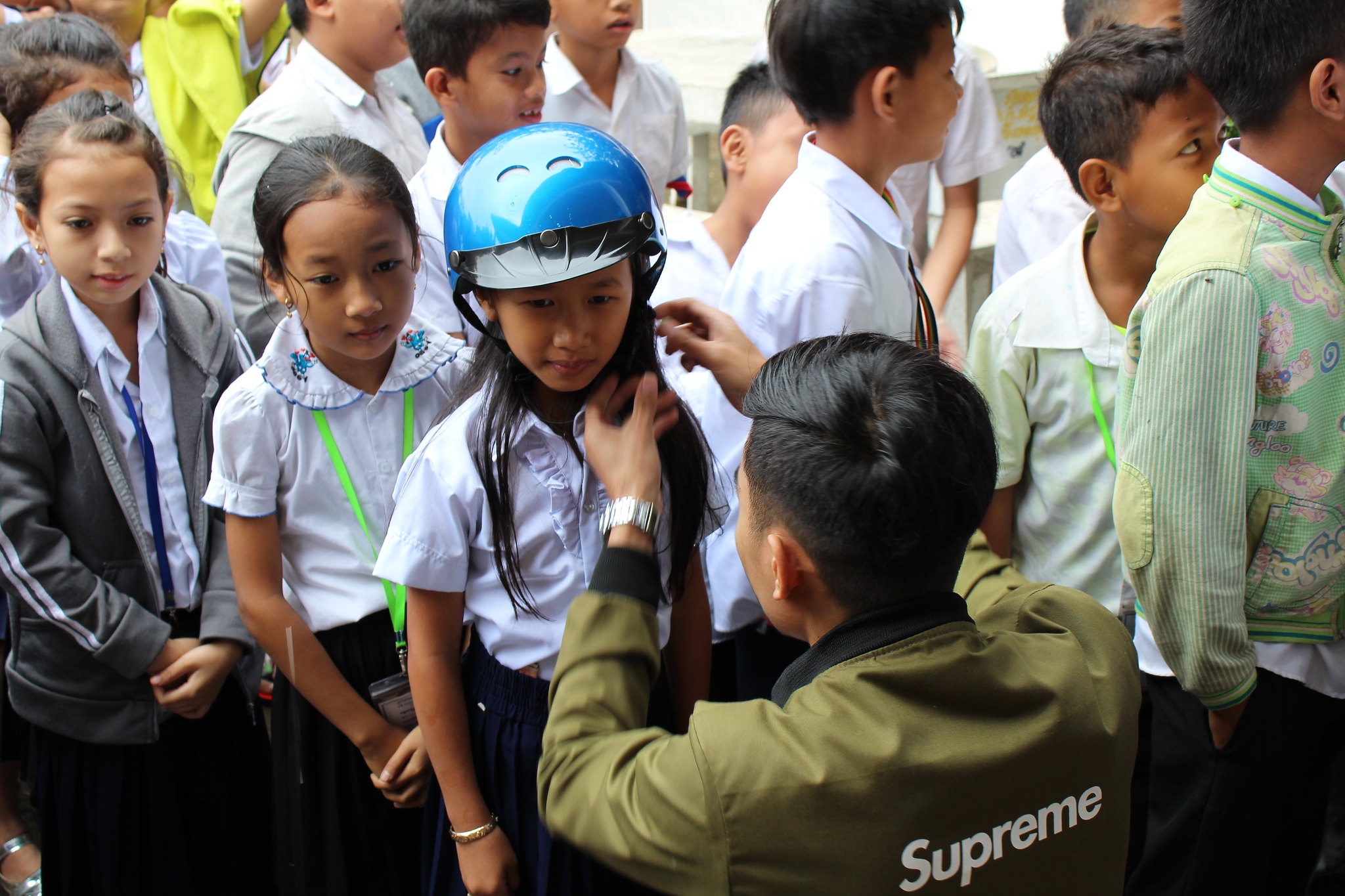 A road safety ambassador assists a student with putting on her new helmet.
