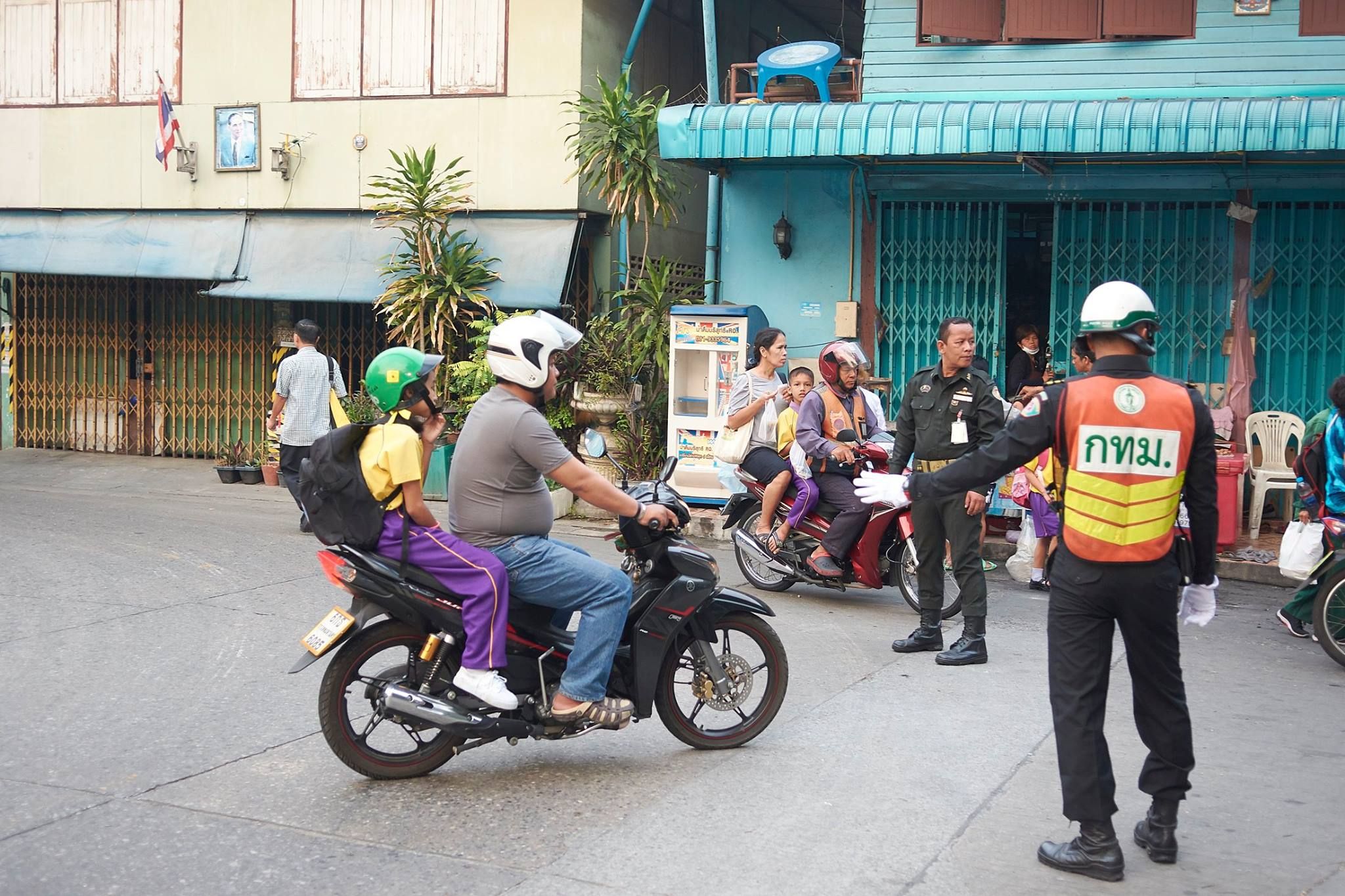 A local law enforcement officer directs traffic in front of Wat Chong Nonsi School in Bangkok.