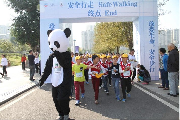 Students together with the Walk Wise panda mascot promote pedestrian safety during the walking parade