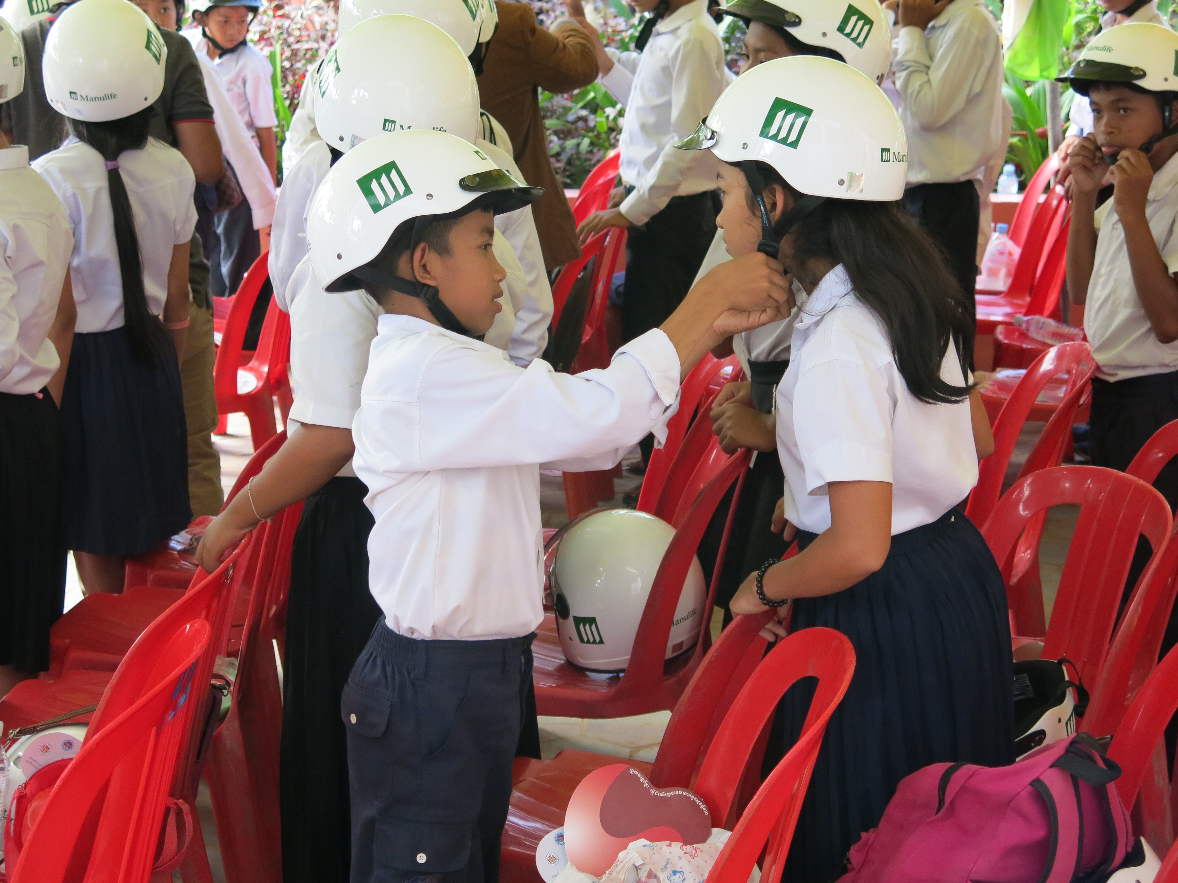 Students at Kessararam Primary School in Siem Reap help each other put on their new helmets.