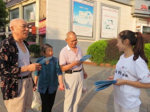 A young volunteer gives a fan promoting pedestrian safety to older community members