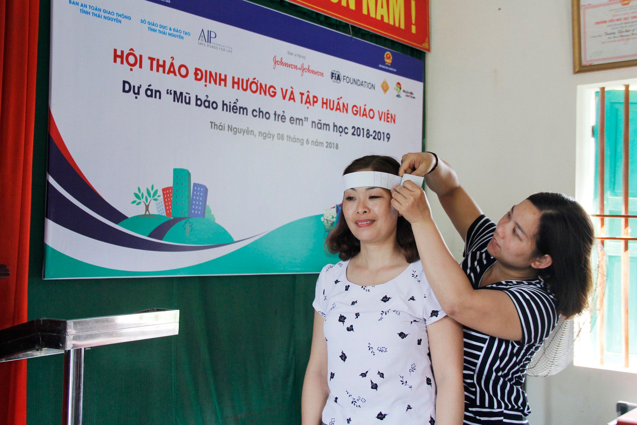 A teacher practices measuring helmet size using a paper ruler.