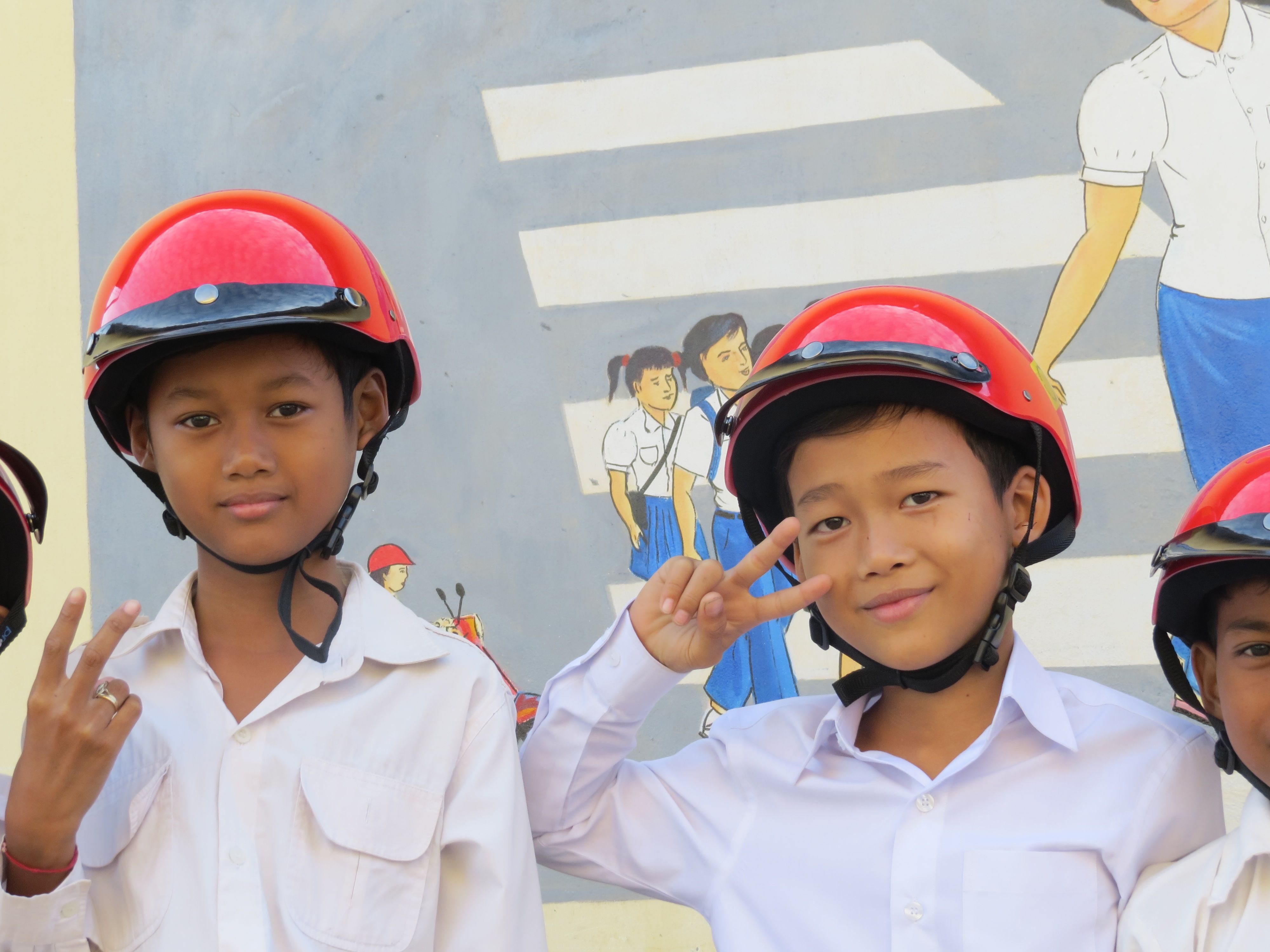 Students stand in front of the road safety mural at Sdao Kanleang Primary School during USAID HSHO Helmet Handover Ceremony on December 24, 2014 in Kandal Province.