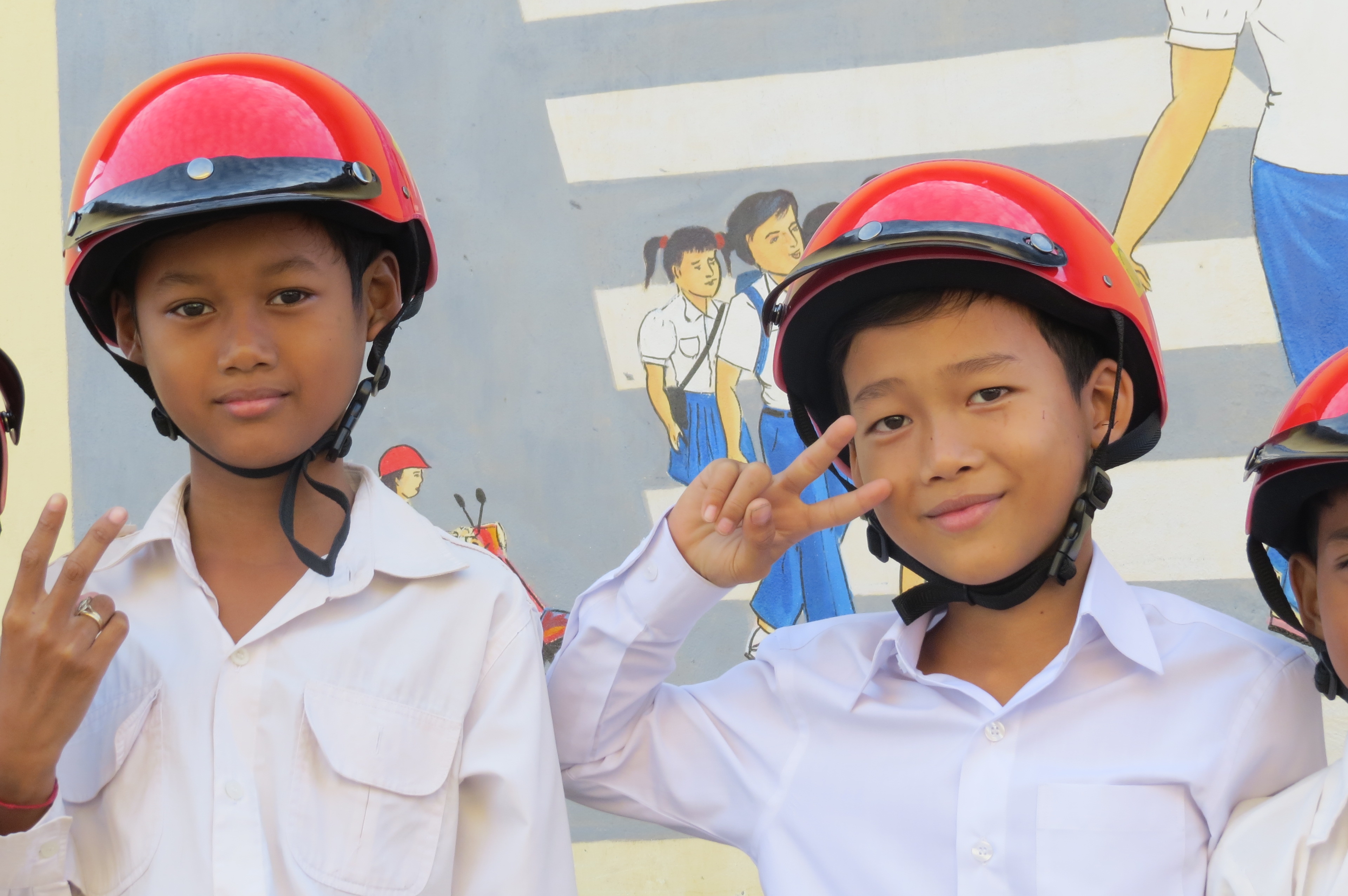 Students stand in front of the road safety mural at Sdao Kanleang Primary School during USAID HSHO Helmet Handover Ceremony on December 24, 2014 in Kandal Province.