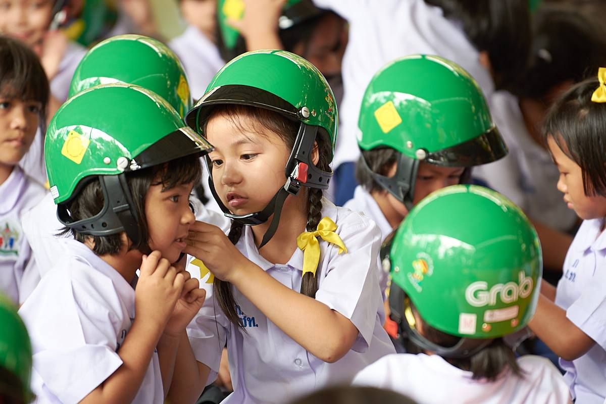 A student from Wat Chong Nonsi School assists her classmate with putting on her new helmet through our Helmet for Kids program.