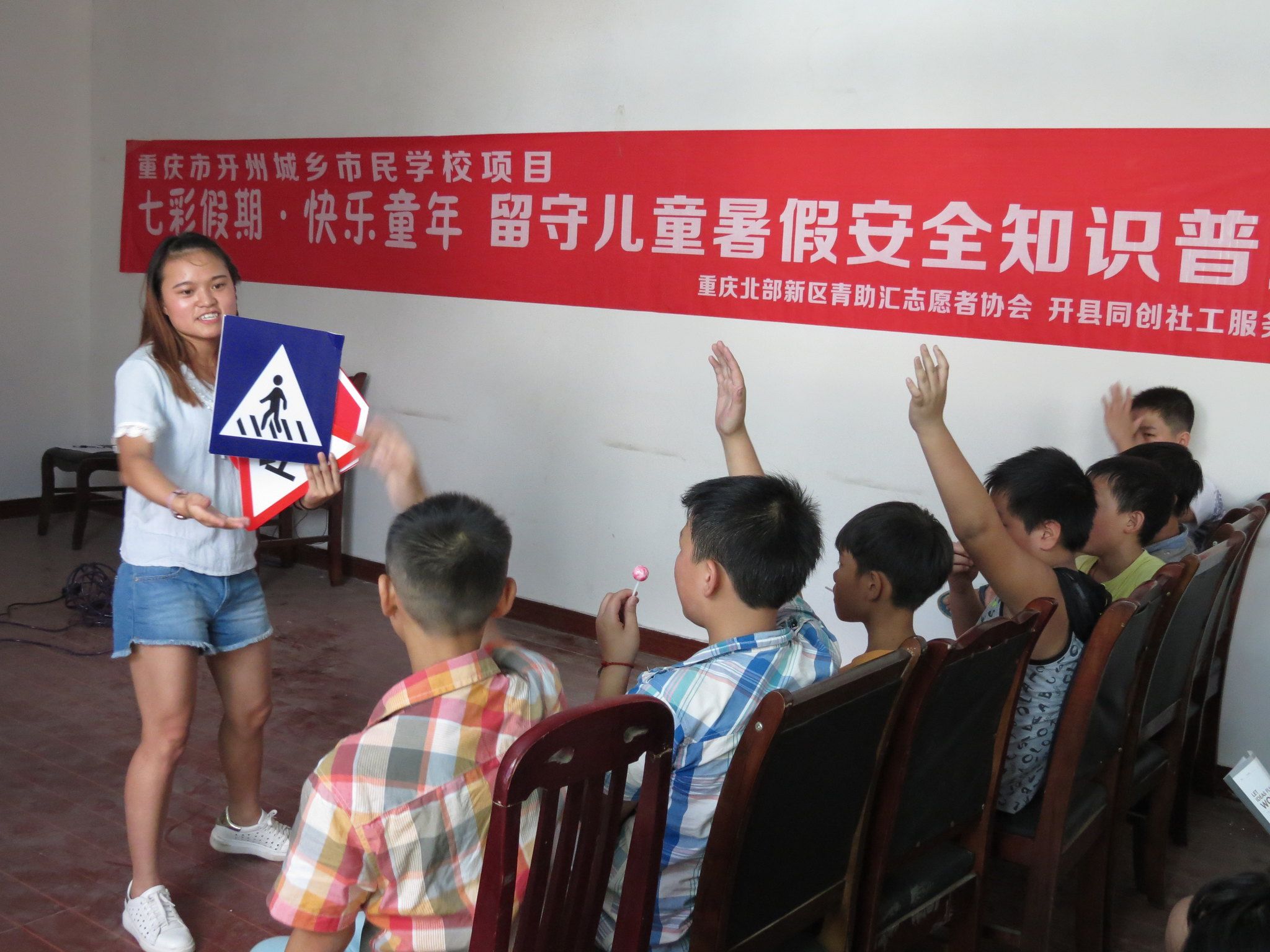 A volunteer teaches children in Kai County how to read traffic signs.