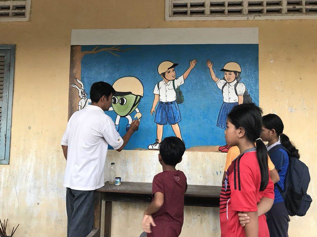 Manulife employees paint positive helmet wearing images on the school wall