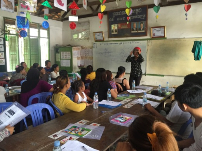 A training course leader demonstrates proper helmet use to a crowd of parents and their children.