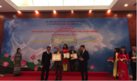 Mr Don Tuan Phong, Vice chairman of VUFO (left), and Mr. Phan Anh Son, Director General of PACCOM (right), present President Greig Craft with an award.