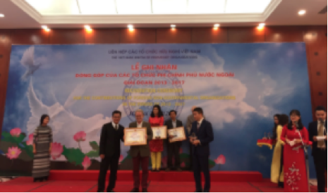 Mr Don Tuan Phong, Vice chairman of VUFO (left), and Mr. Phan Anh Son, Director General of PACCOM (right), present President Greig Craft with an award.