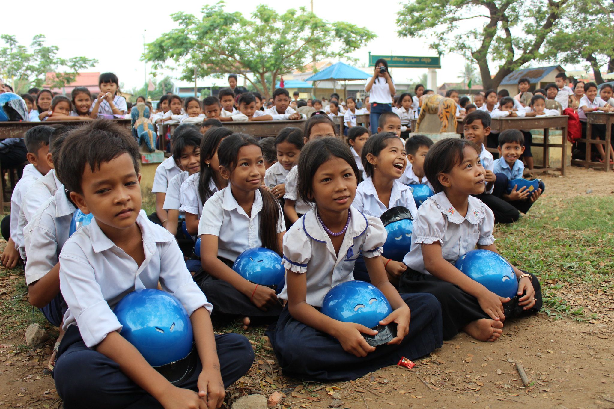 Students from Batheay Primary School laugh at an entertaining performance during the helmet handover ceremony.