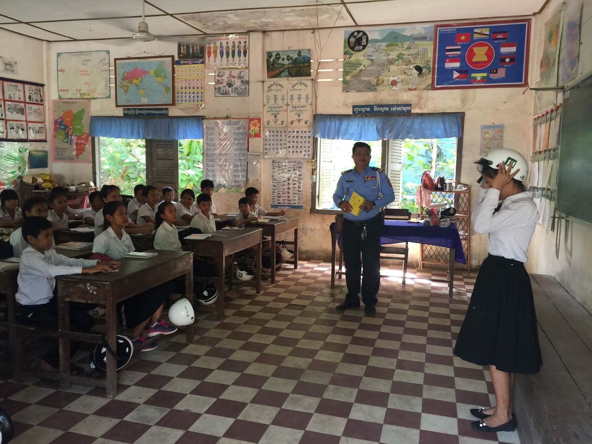 A traffic officer teaches a student at Kessararam Primary School how to properly put on a helmet.
