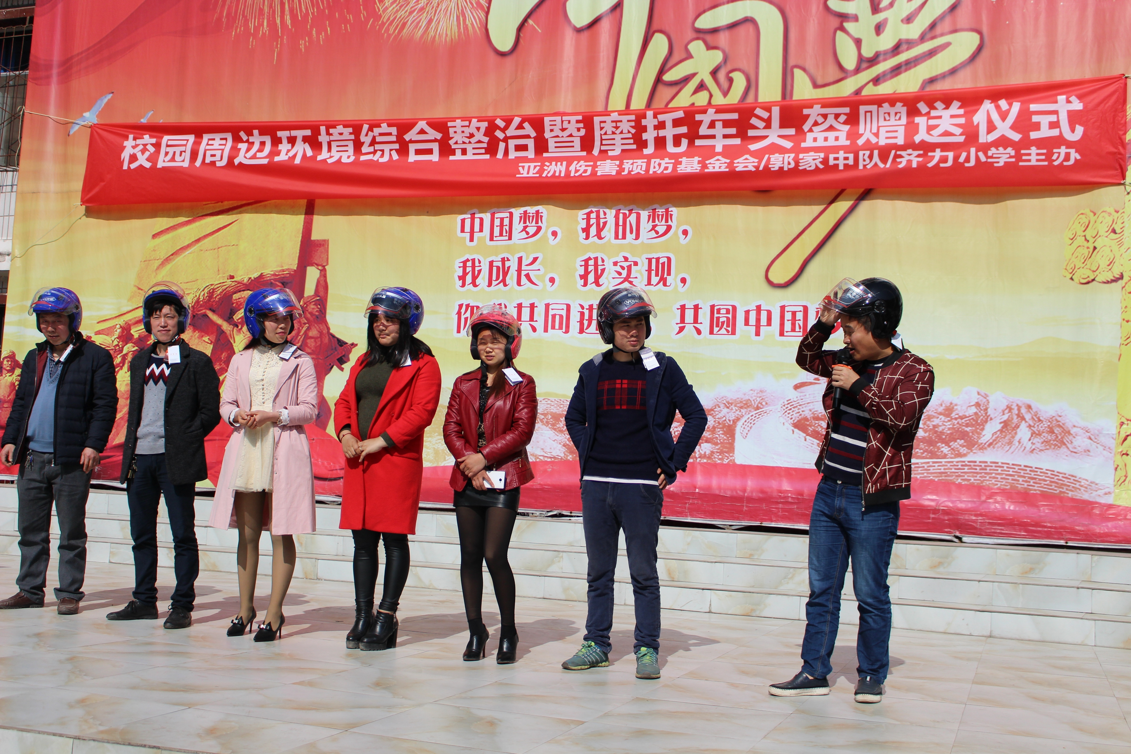 Parents participate in a helmet-wearing demonstration after receiving their new safety equipment.