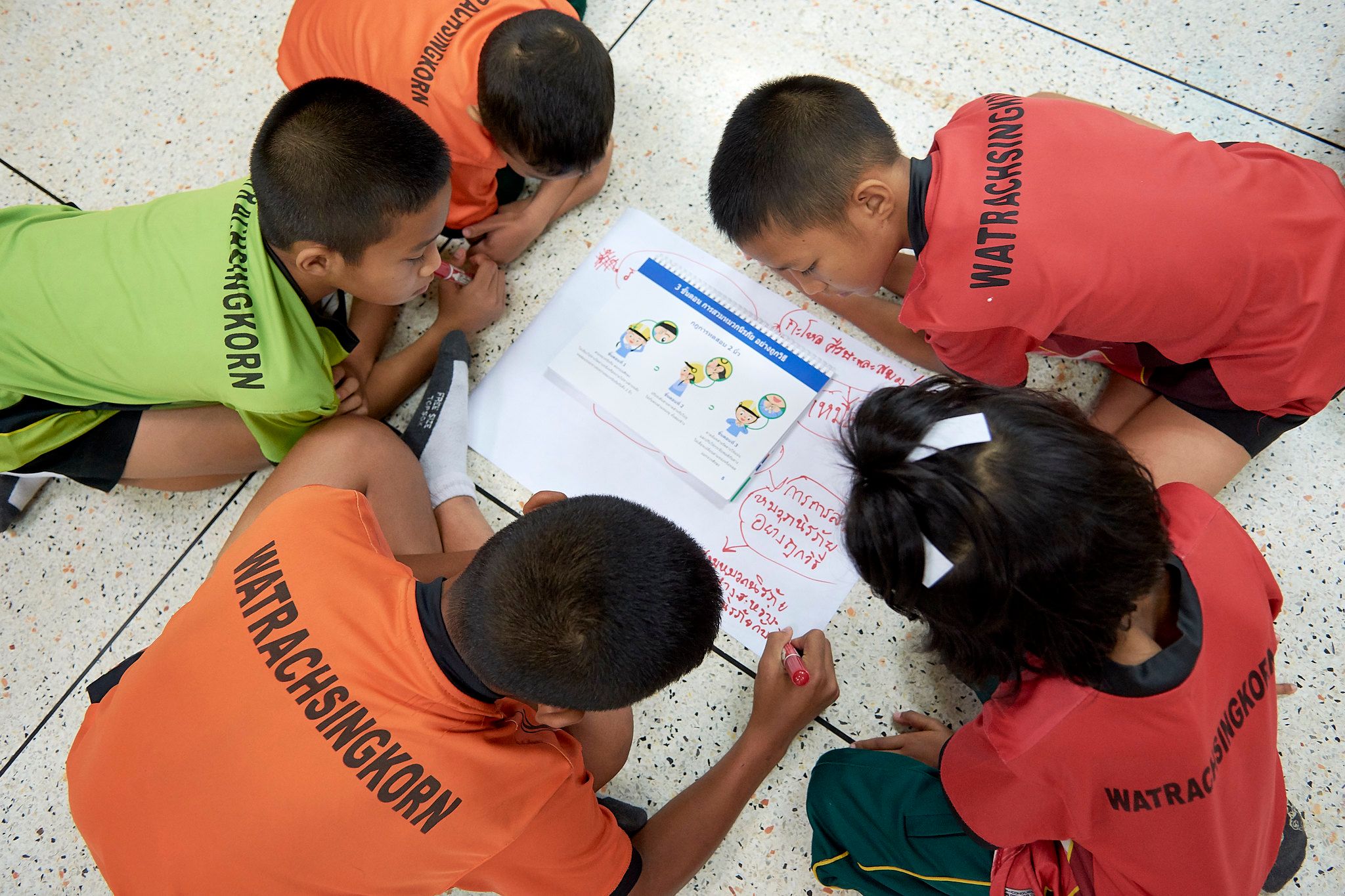 Students from Wat Rachasingkorn School learn steps for properly wearing a helmet.