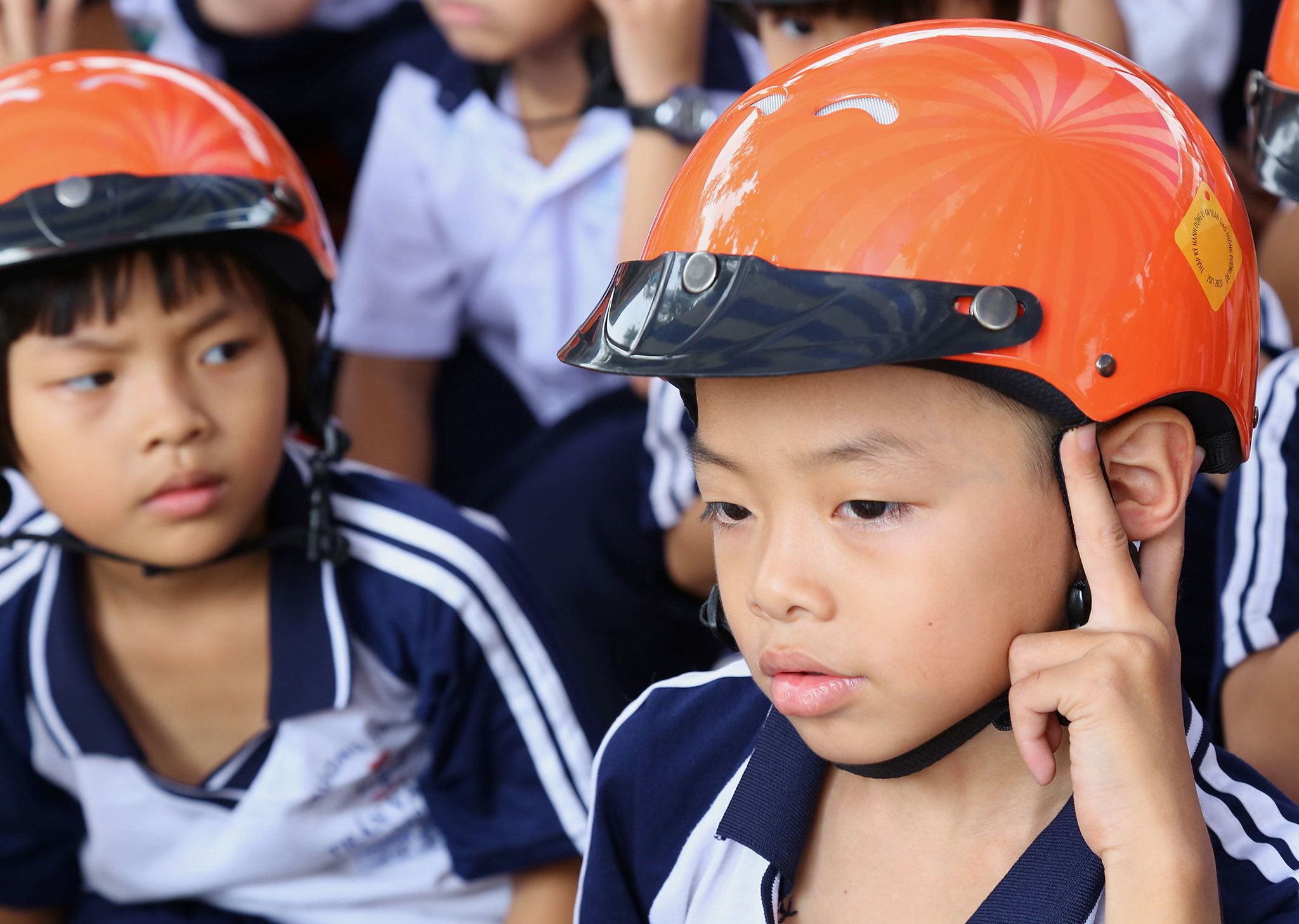 Students practice the proper steps for wearing a helmet at the Safety Delivered School Visit.