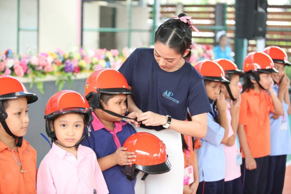 Ms. Anyarin Terathananpat, Thai actress, supports students in properly wearing their helmets during a helmet-use demonstration.
