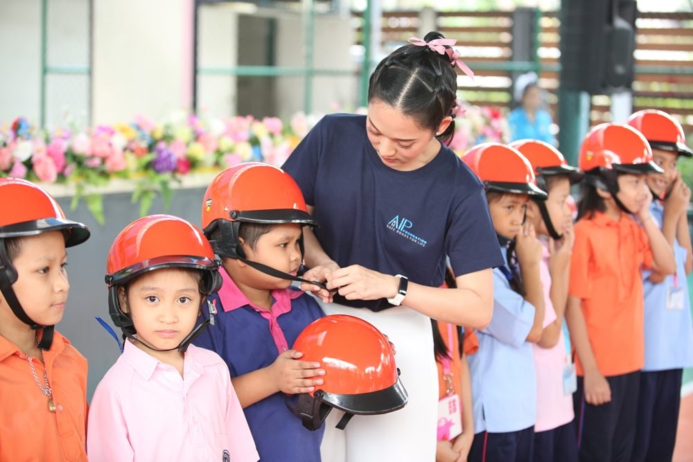 Ms. Anyarin Terathananpat, Thai actress, supports students in properly wearing their helmets during a helmet-use demonstration.