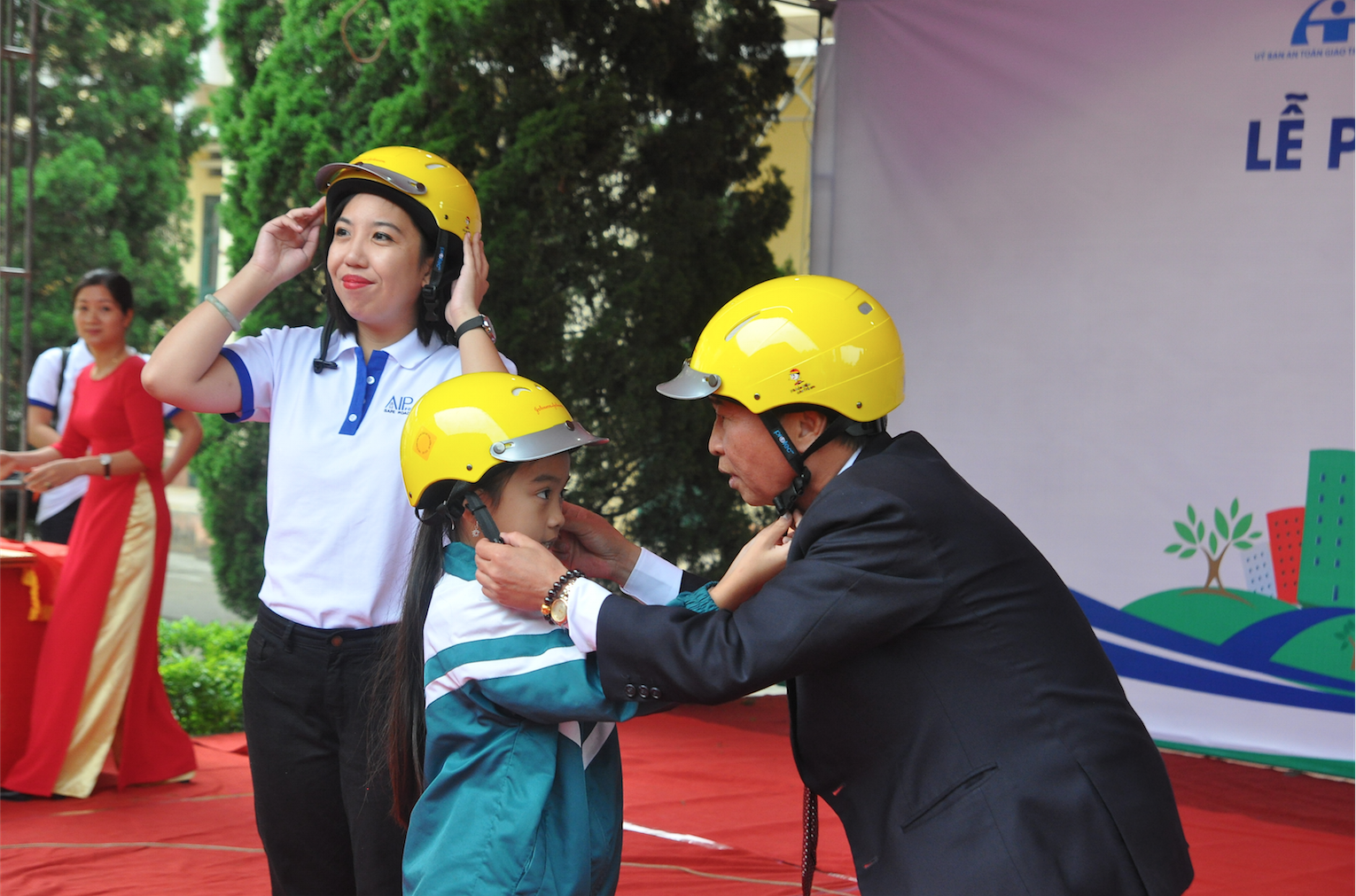 Mr. Nguyen Quang Trung, Government Affairs Director for Johnson & Johnson Vietnam, and Samantha Serafica of AIP Foundation demonstrate the correct helmet-wearing steps for the students.