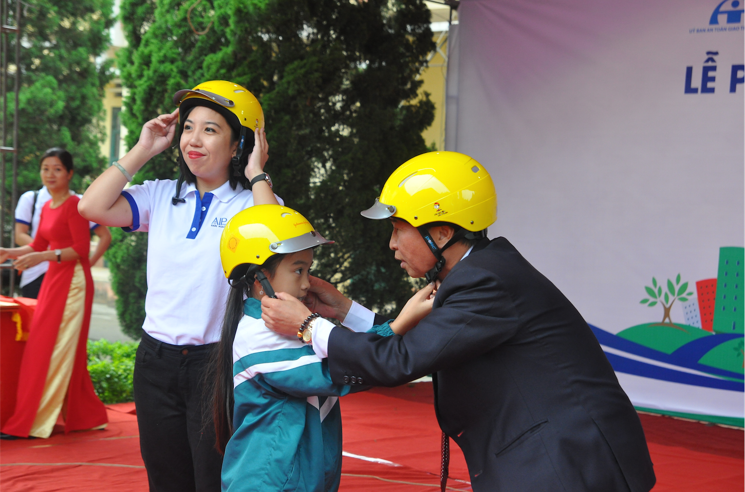 Mr. Nguyen Quang Trung, Government Affairs Director for Johnson & Johnson Vietnam, and Samantha Serafica of AIP Foundation demonstrate the correct helmet-wearing steps for the students.