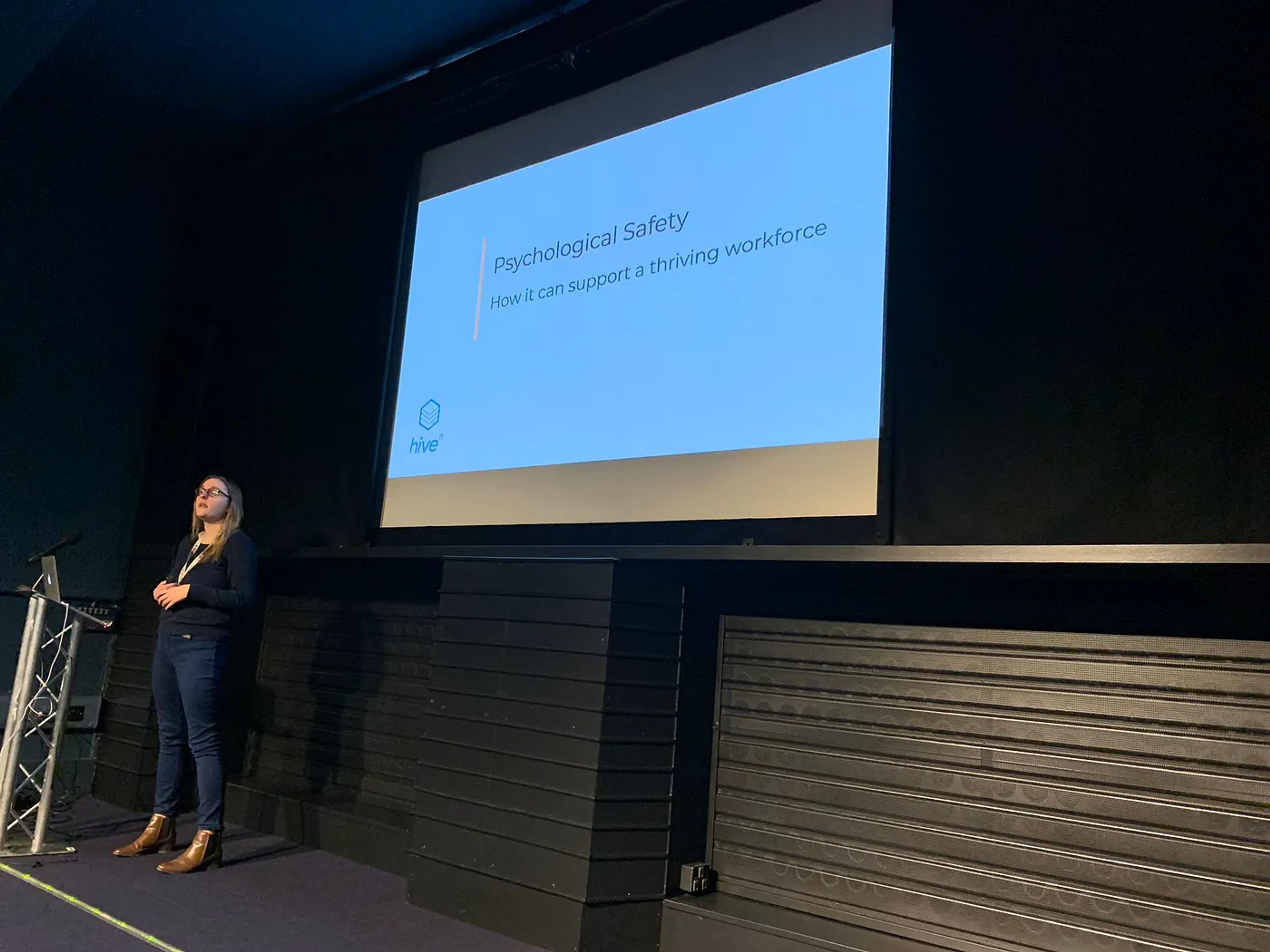 A picture of Liz stood up next to a slide show presenting her talk.