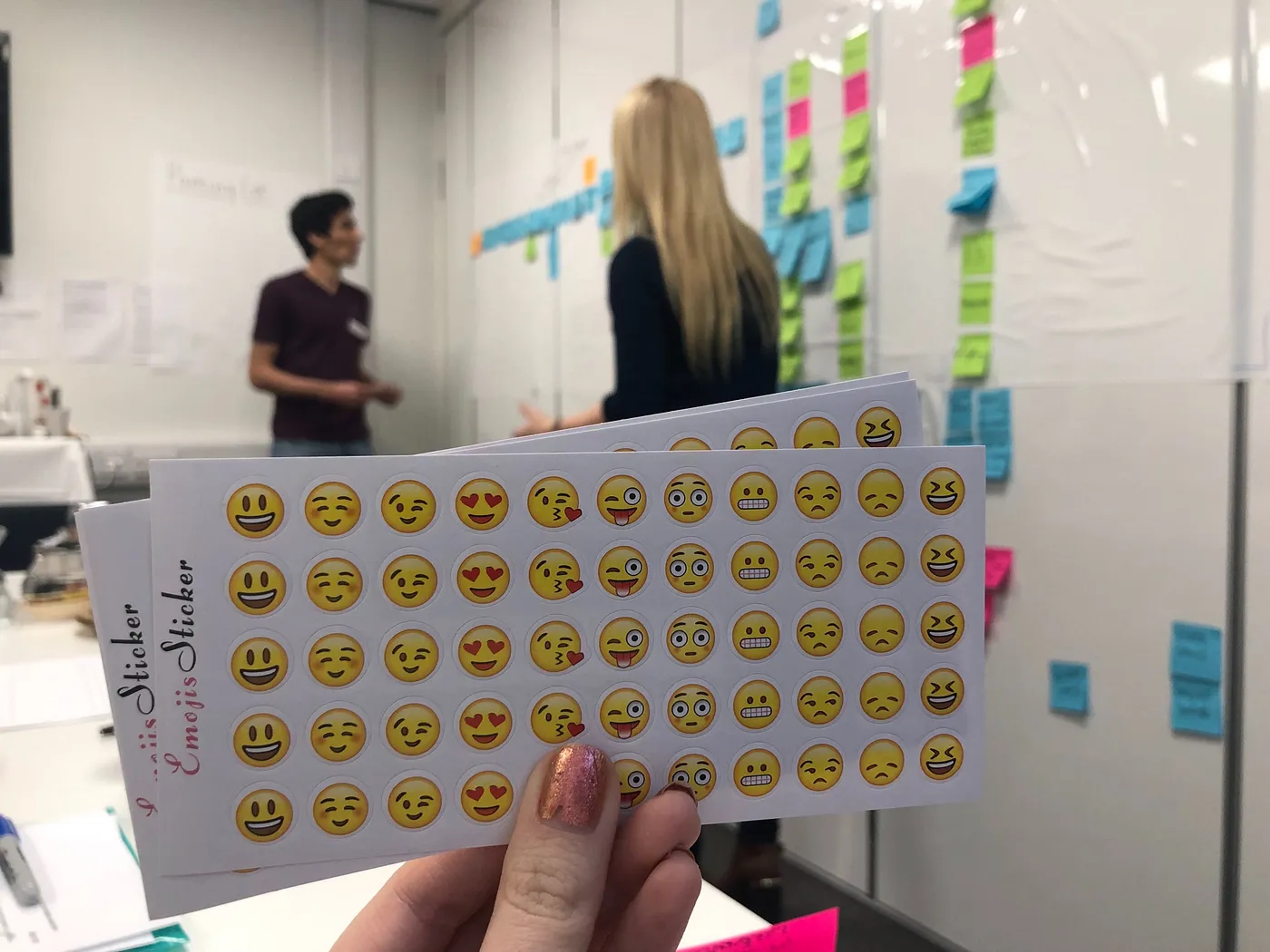 Picture of a hand holding emoji stickers in a workshop