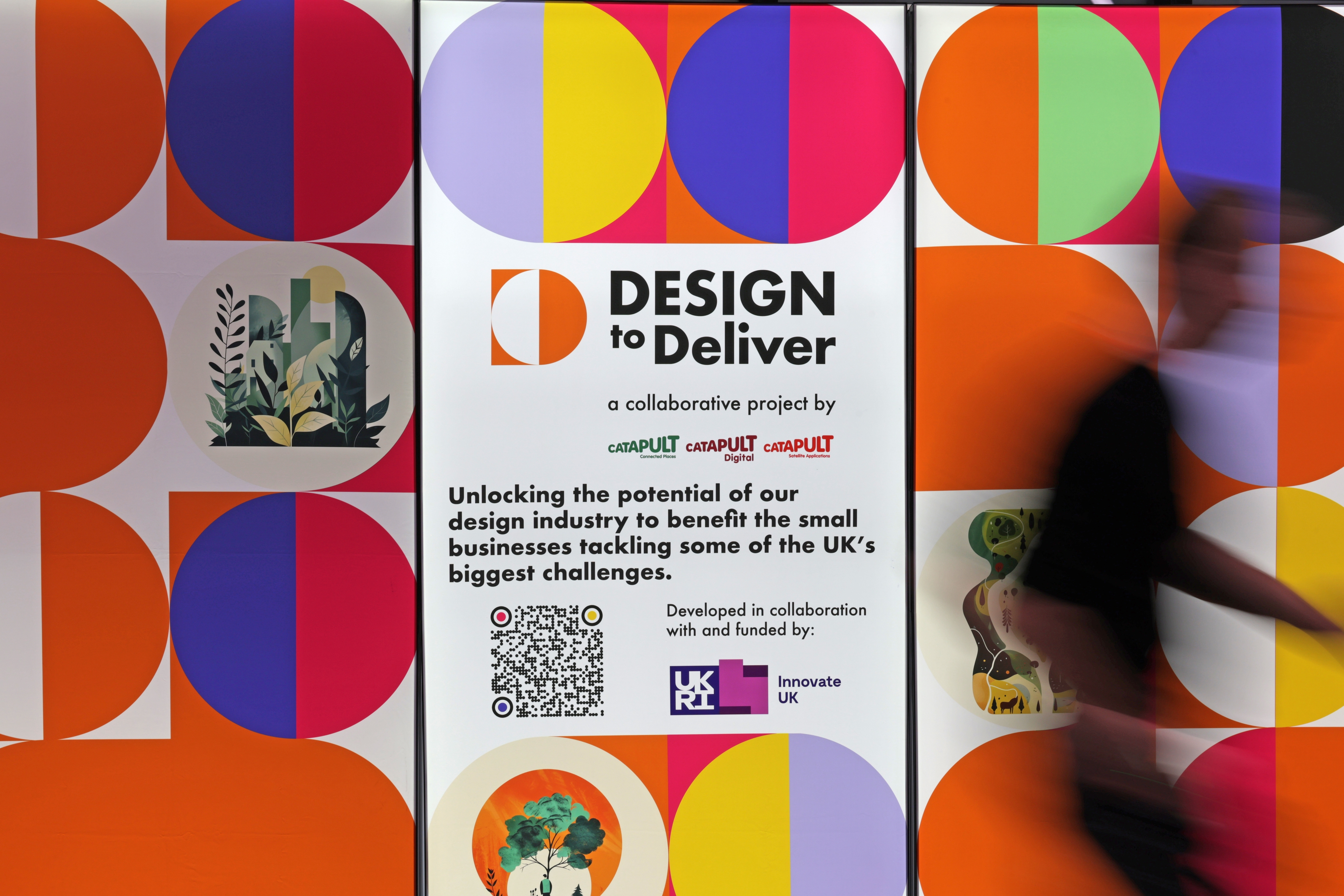 A multi coloured Design to Deliver signpost from the event. Featuring the Catapult Network logos and Innovate UK logo. The image has decorative orange, yellow, pink and purple circles.