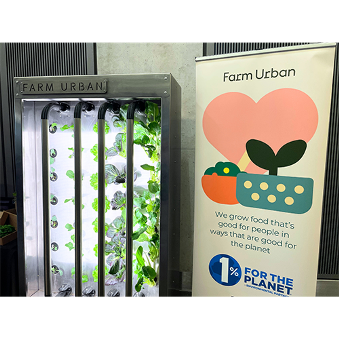 Image of a contraption that is growing food along with a signpost which says, 'Farm Urban, we grow food that's good for people in ways that are good for the planet'.