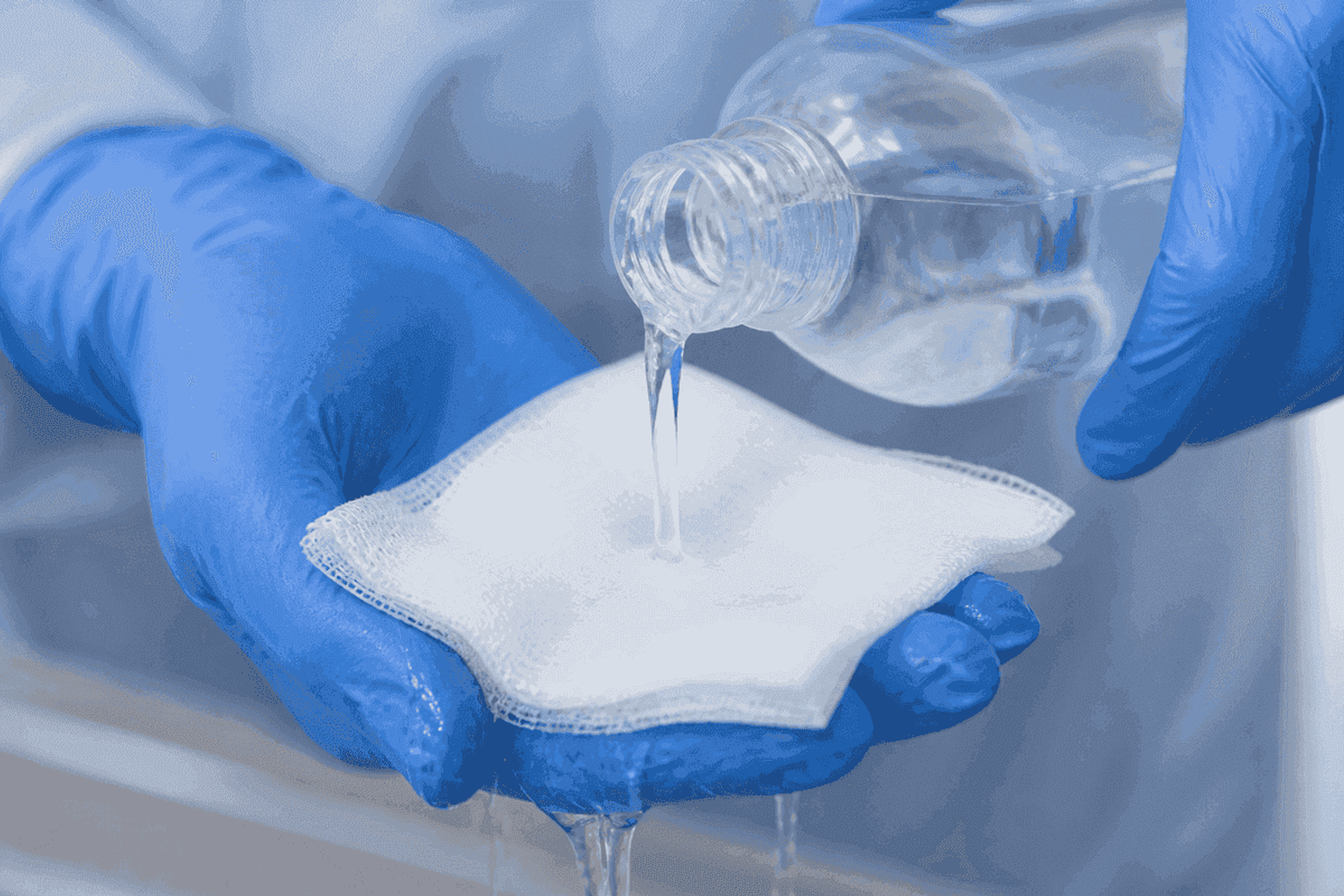 Gloved hands pouring cool saline onto clean gauze.