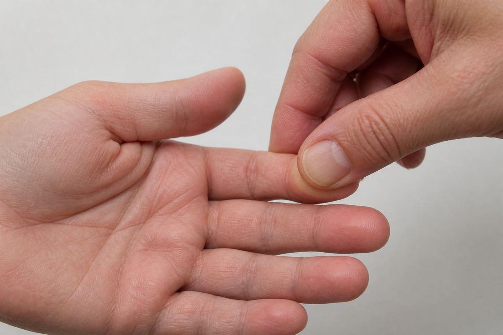 Close-up of a fingertip being gently pressed to assess capillary refill.