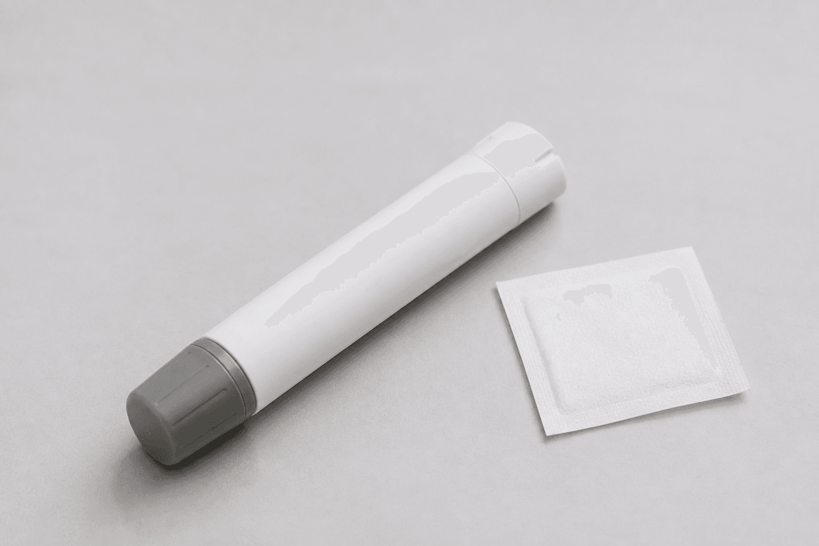 Blank epinephrine auto-injector trainer and alcohol wipe.